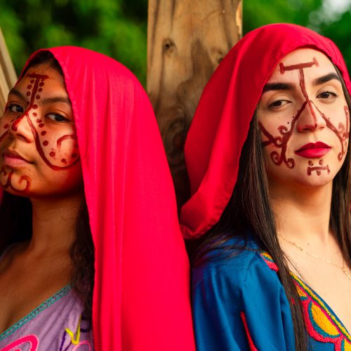 Dos mujeres wayuu con mantas rojas y pintura facial tradicional en La Guajira