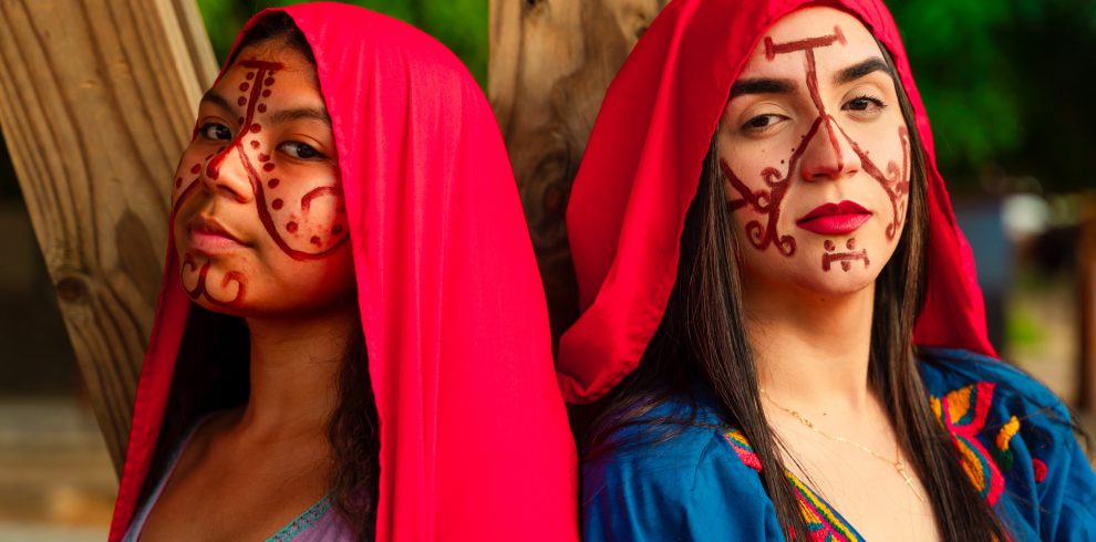 Dos mujeres wayuu con mantas rojas y pintura facial tradicional en La Guajira